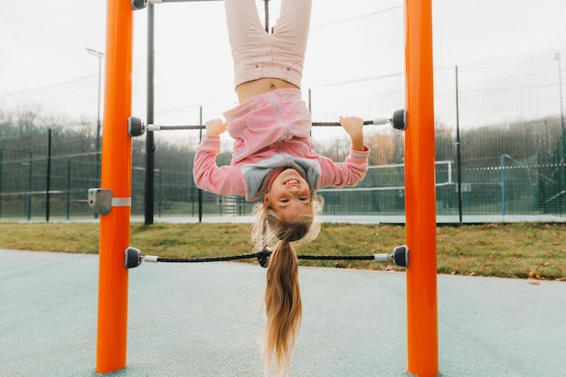 Premium Photo | A young girl on a climbing frame hangs upside down on a ...