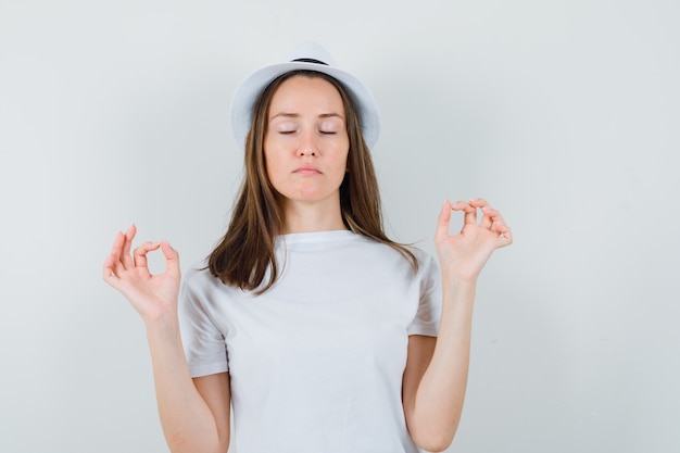 Free Photo | Young girl doing meditation with closed eyes in white t ...