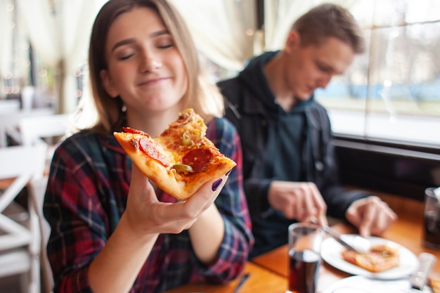 Premium Photo | Young girl eating a slice of pizza indoors
