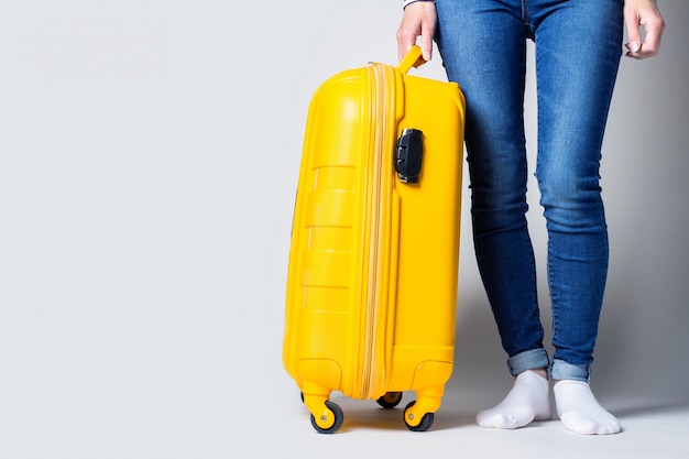 Premium Photo | Young girl holding a yellow suitcase on a light background