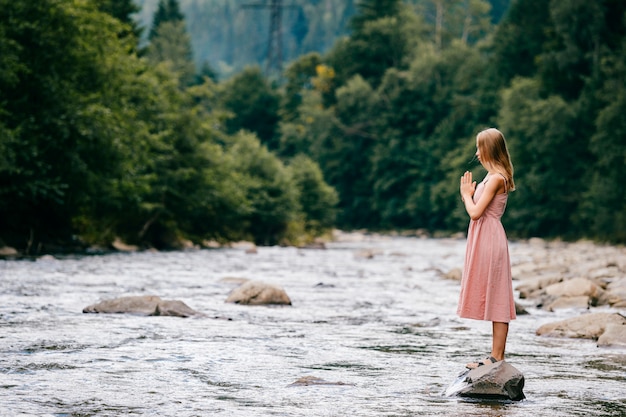 Premium Photo | Young girl praying while standing on stone in the river ...