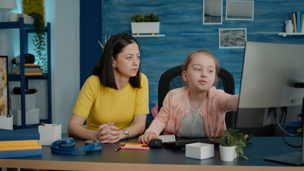 Young girl receiving help with homework from mother Free Photo