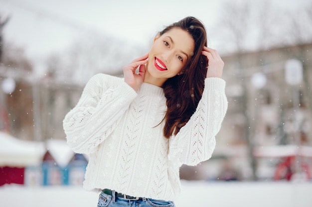Young girl in a white sweater standing in a winter park Free Photo