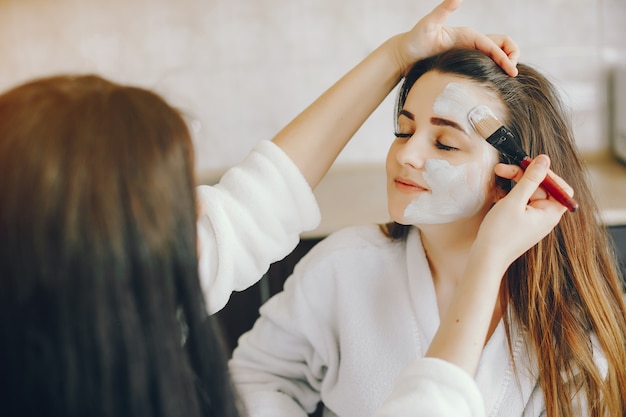 young girl with beautiful hands puts a refreshing mask on her girlfriend's face with a brush Free Photo