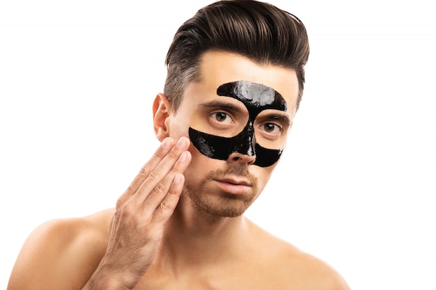 Premium Photo | Young guy with a black charcoal mask on his face on white.