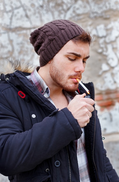 Premium Photo | Young guy with wool cap smoking