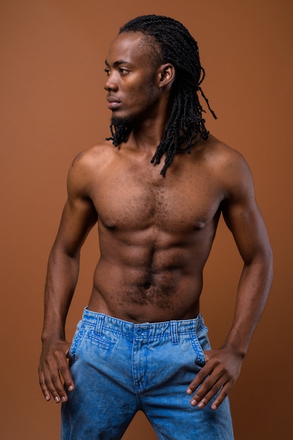 茶色の背景に対して上半身裸の若いハンサムなアフリカ人 プレミアム写真