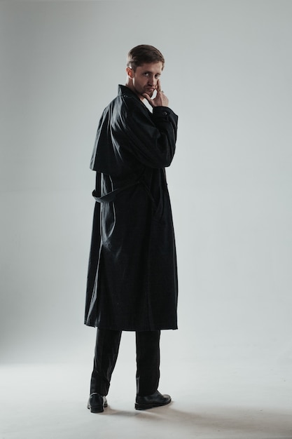 Young and handsome caucasian man posing in a black trench