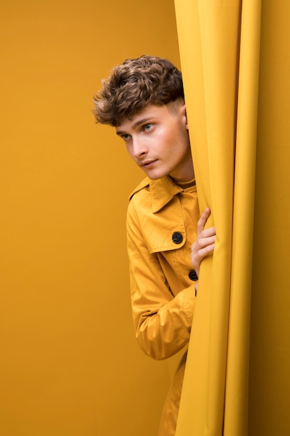 Free Photo | Young handsome man next to a curtain in a yellow scene