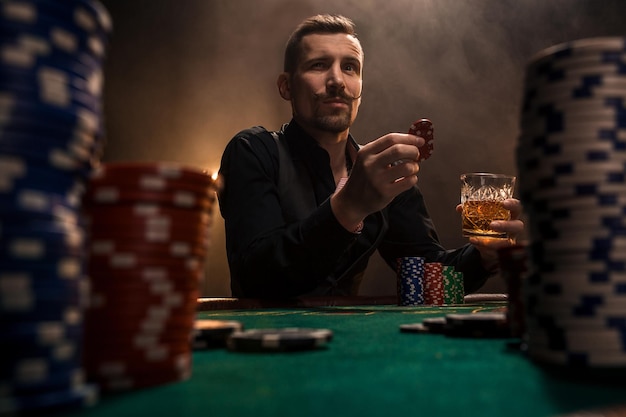 Premium Photo | Young handsome man sitting behind poker table with ...