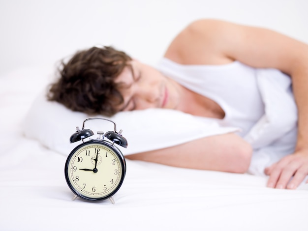 Free Photo | The young handsome man sleeping with alarm clock near his head