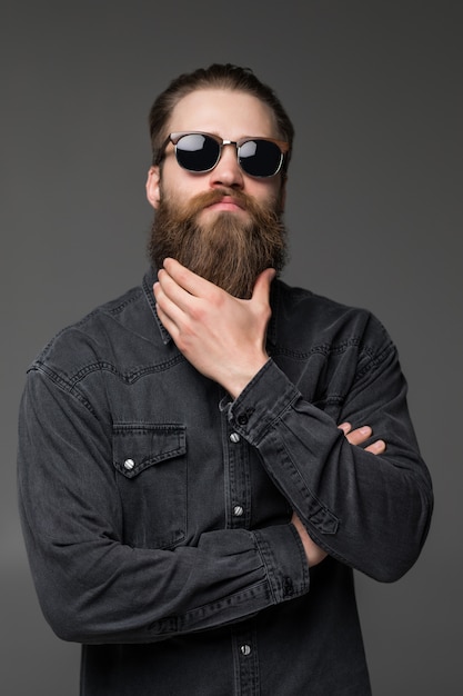 Premium Photo | Young handsome man in sunglasses touch his long beard ...