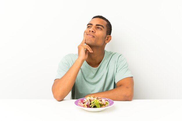 Young Handsome Man With Salad In A Table Thinking An Idea