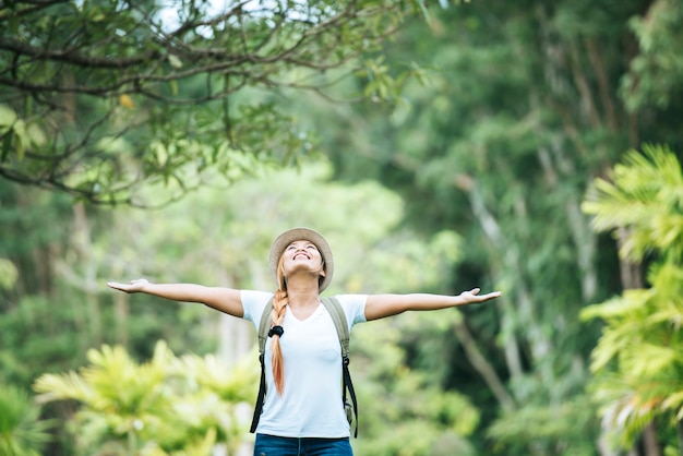 Young happy woman with backpack raising hand enjoy with nature. Free Photo