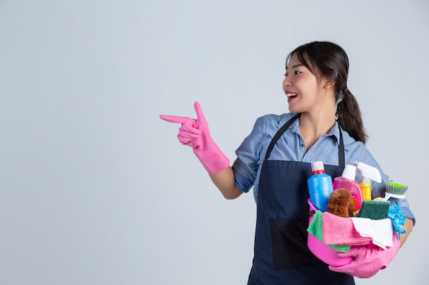 Young housewife is wearing yellow gloves while cleaning with the product of clean on white wall. Free Photo