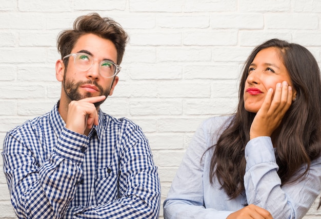 Premium Photo | Young indian woman and caucasian man couple thinking and looking up, confused about an ide