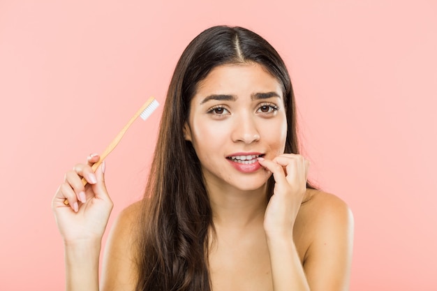 Premium Photo | Young indian woman holding a toothbrush biting ...