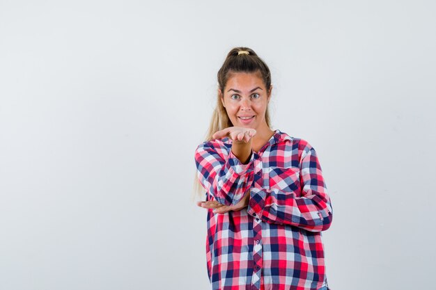 Free Photo Young Lady Keeping Hand Outstretched In Checked Shirt And Looking Cheery Front View