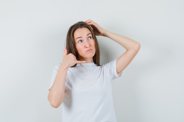 Free Photo | Young lady showing phone gesture while scratching head in ...