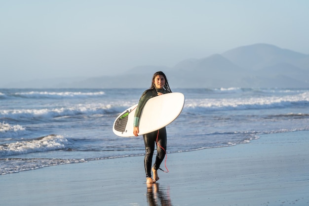 Premium Photo | Young latin surfer walking on the beach with surfboard