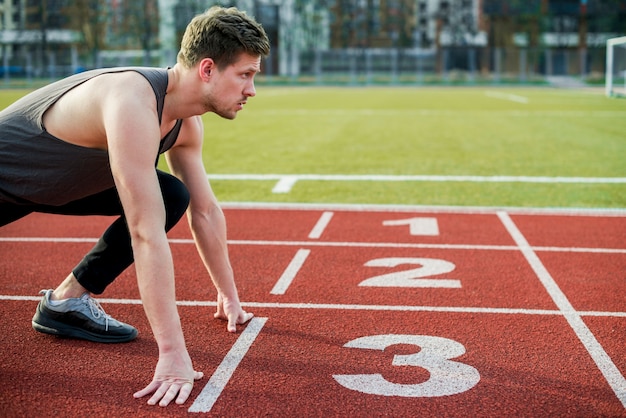 Young male athlete ready to run taking position at the start line Photo ...