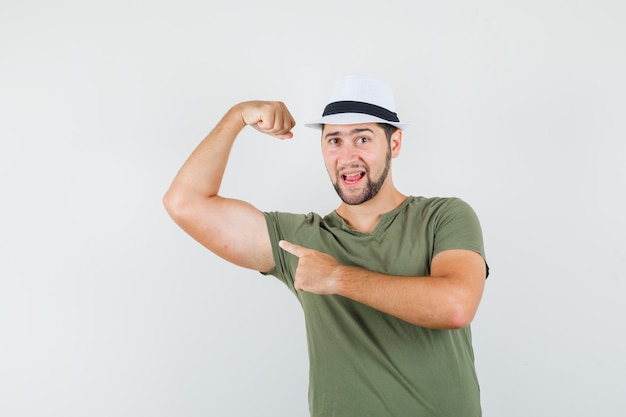 Free Photo | Young male pointing at muscles in green t-shirt, hat and ...