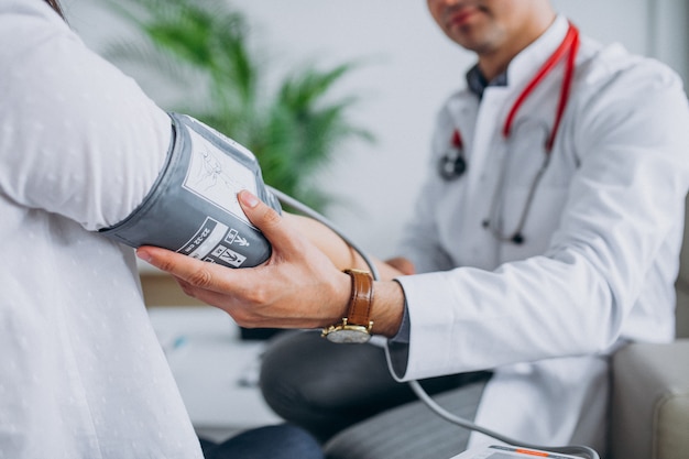 Young male psysician with patient measuring blood pressure Free Photo