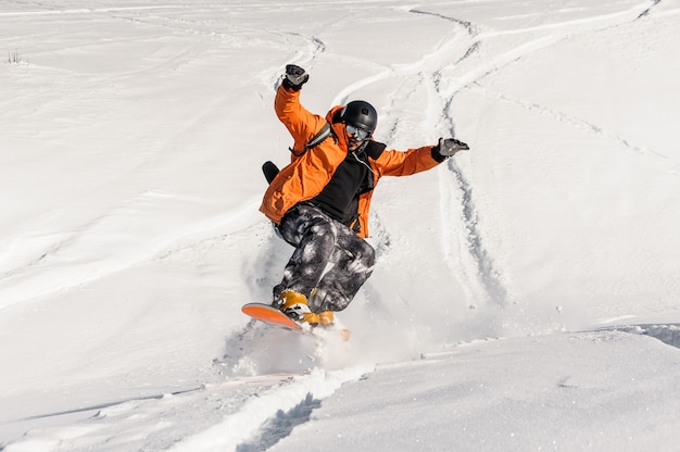 Premium Photo | Young male snowboarder in orange sportswear jumping on ...