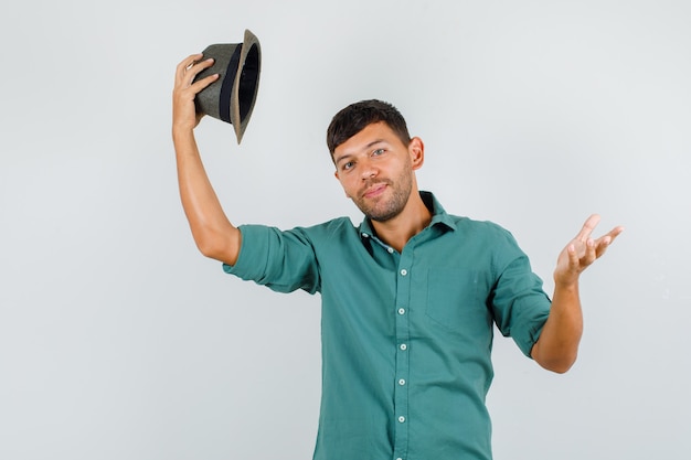 free-photo-young-male-taking-off-his-hat-in-shirt-and-looking-cheerful