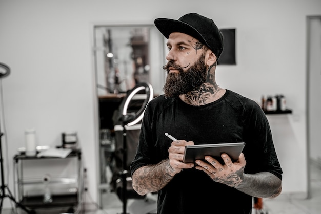 Premium Photo | Young male tattoo artist with beard holding pencil and ...