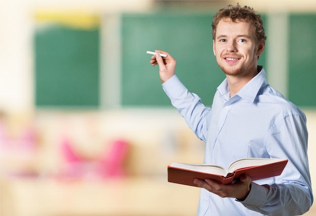 Premium Photo | Young male teacher standing with book