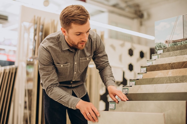 Young man choosing tiles at building market Free Photo