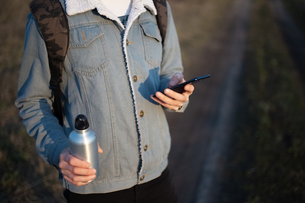 Download Premium Photo Young Man In Denim Jacket With Smartphone And Aluminium Bottle In His Hands