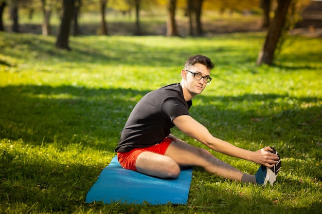 Premium Photo | Young man in glasses training yoga outdoors. sporty guy ...