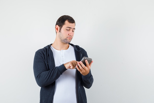 Free Photo | Young man holding calculator and doing some operations on ...