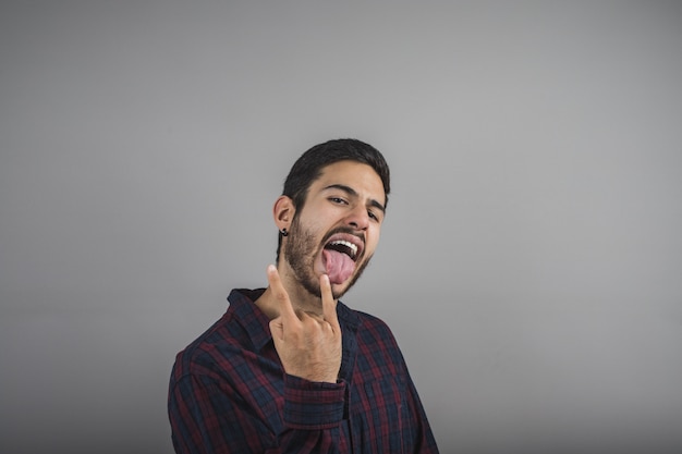 Premium Photo | Young man making the horns and sticking out his tongue