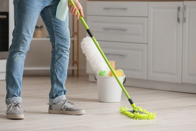 Premium Photo | Young man mopping floor in kitchen