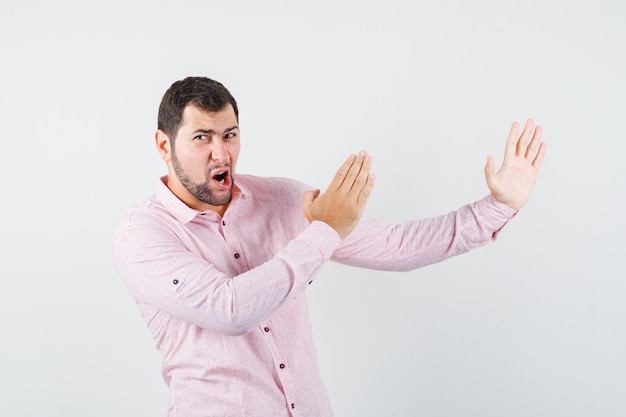 Free Photo | Young man in pink shirt showing karate chop gesture and ...