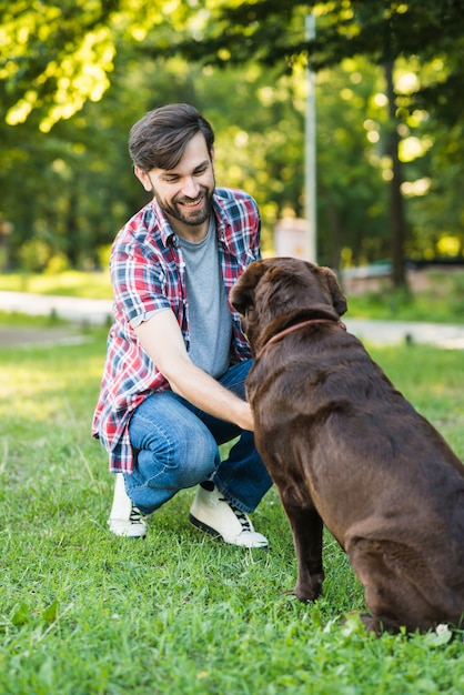 Free Photo | Young man playing with his dog on green grass