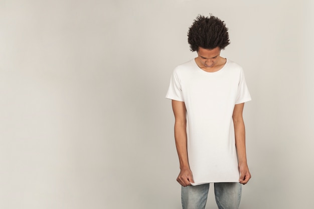 Young man pulling on t-shirt Photo | Free Download
