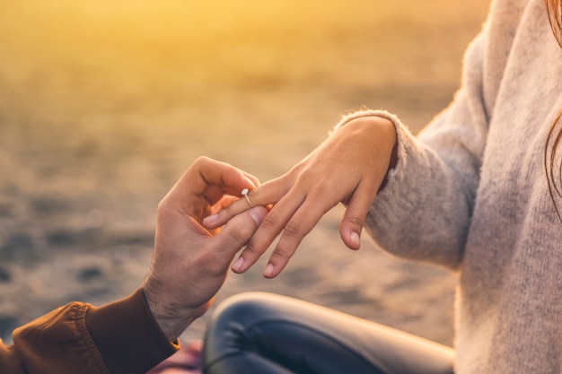 Young man putting wedding ring on woman finger