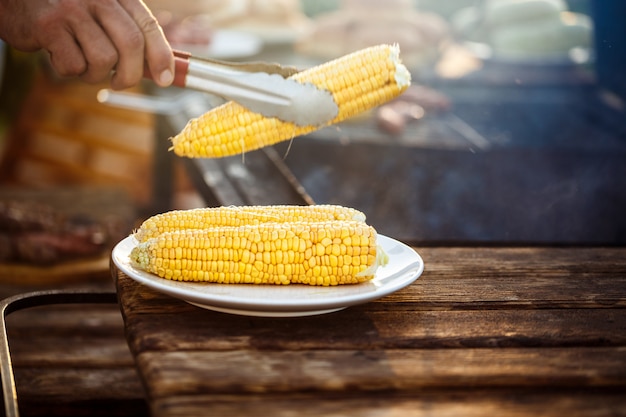 Fiatal férfi kukoricát sült grill. Ingyenes fénykép