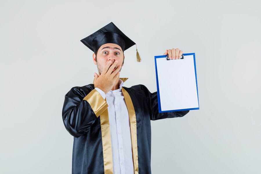 Free Photo | Young man showing clipboard in graduate uniform and ...