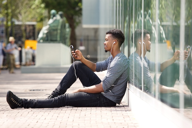Premium Photo Young Man Sitting On Ground Listening To Music On Smart Phone