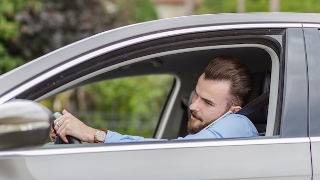 Free Photo | Young man sitting inside car talking on mobile phone