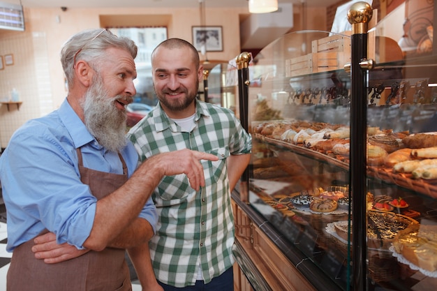 Premium Photo | Young man talking to a senior baker while shopping for ...