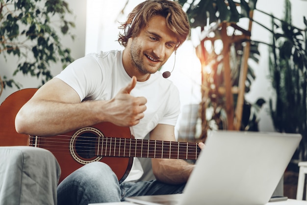 Premium Photo | Young man watching guitar tutorial on his laptop