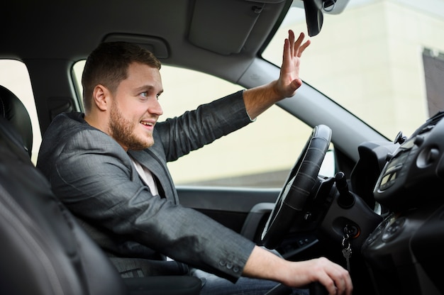 Young man at the wheel greeting someone Free Photo