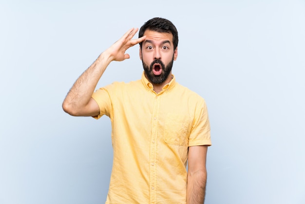 Young man with beard over isolated blue has just realized something and has intending the solution Premium Photo