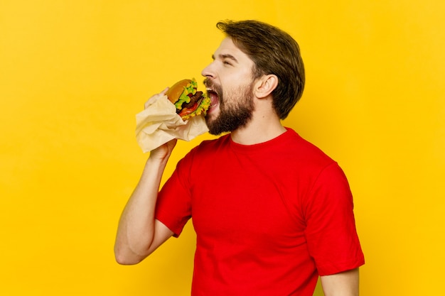 Young man with a juicy hamburger in his hands, a man eating a burger Premium Photo